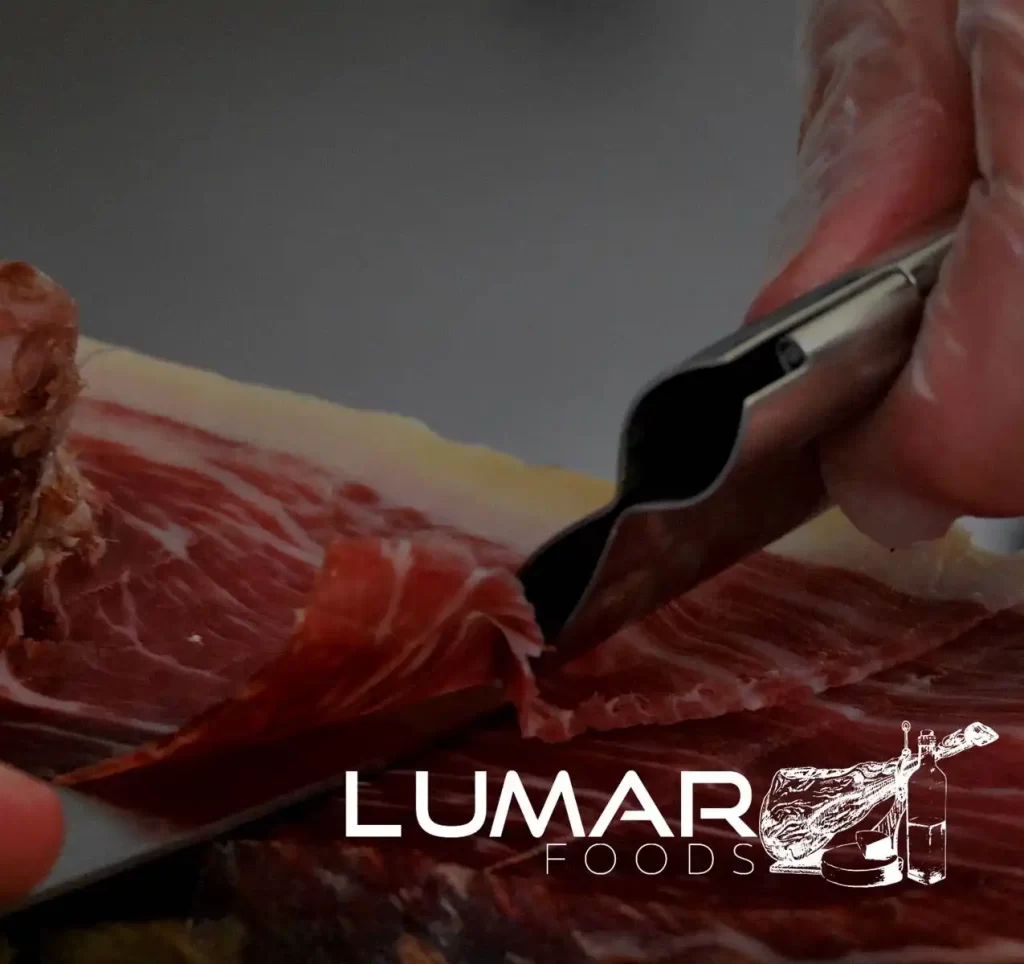 Primer plano de mano de maestro cortador realizando el corte artesanal de lonchas de jamón ibérico